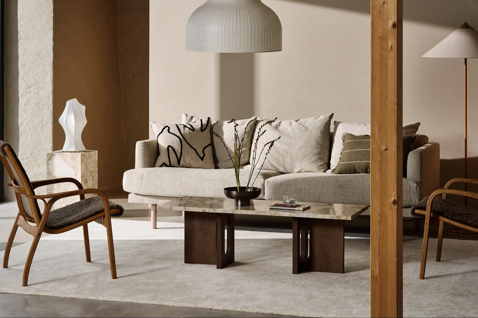 Modern living room with light sofa, marble coffee table, wooden armchairs, and neutral decor.