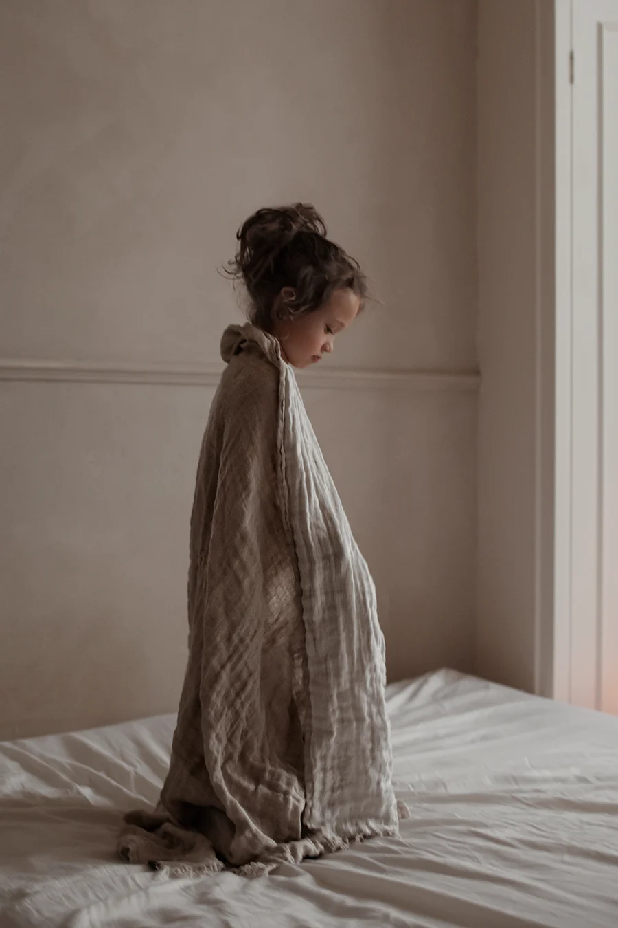 A boy stands in a window drapped in the Hannelin linen throw from Himla.