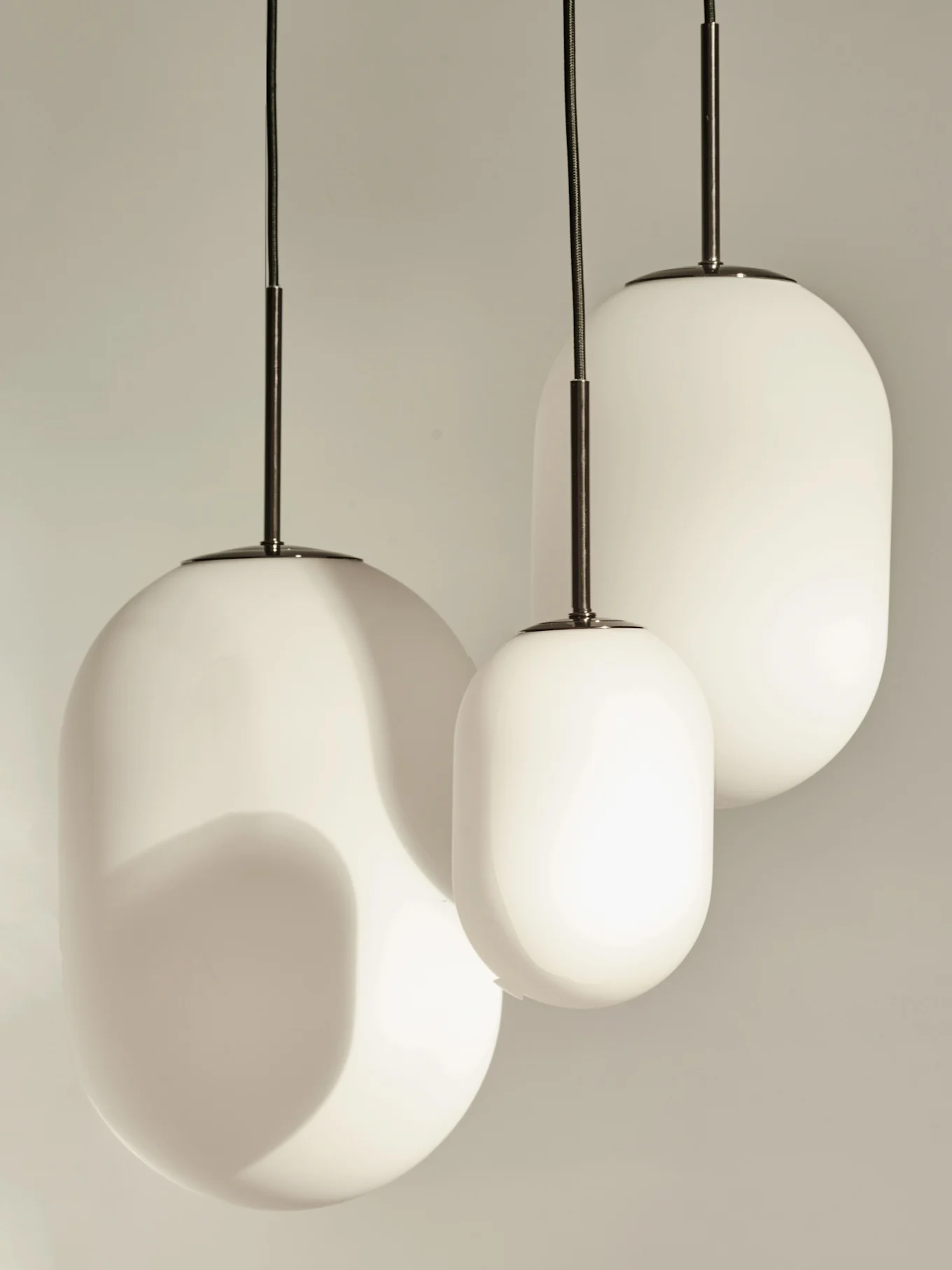 Three modern white pendant lights with rounded, elongated glass shades.
