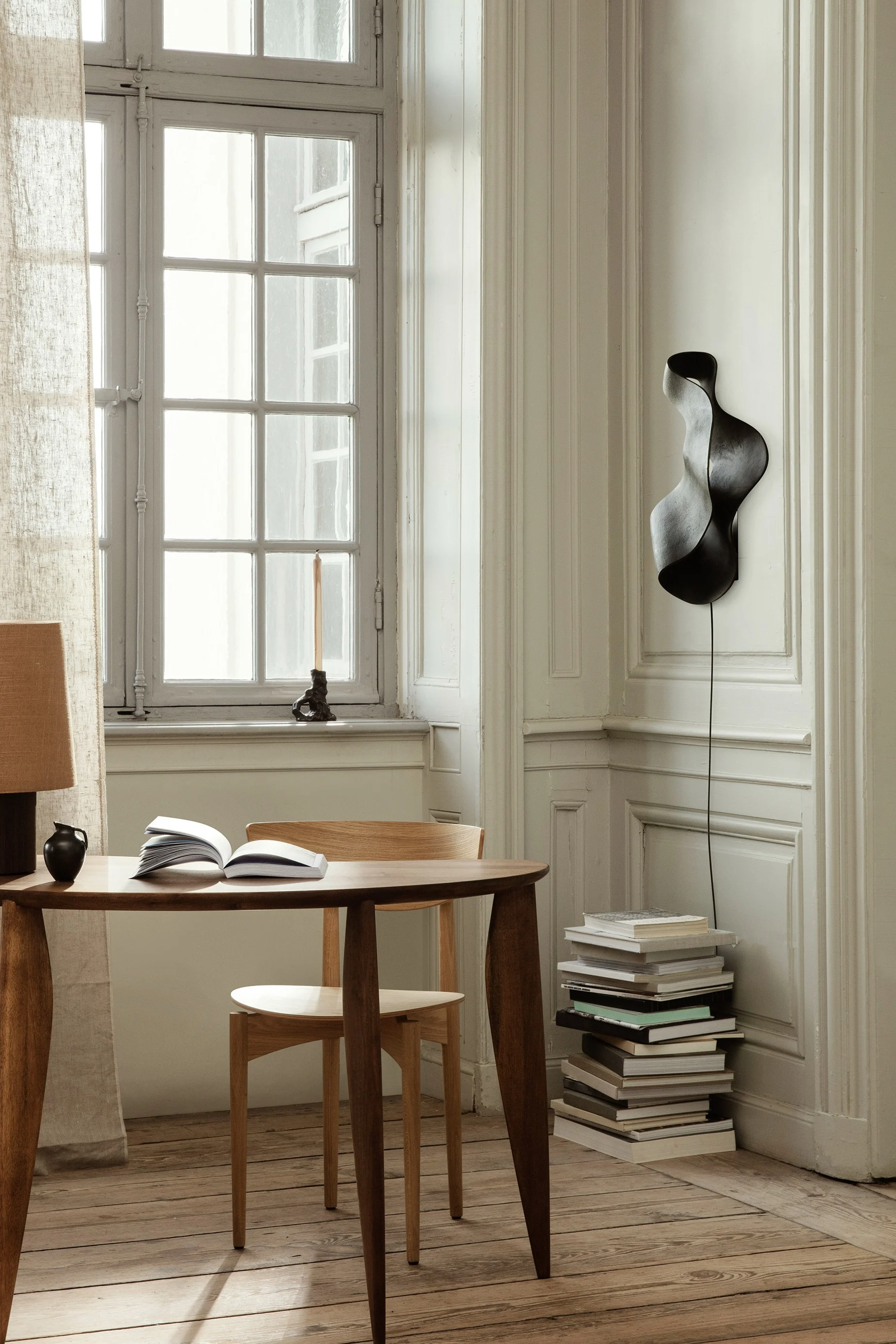 Update your home with these modern lighting ideas like the Oyster wall lamp from Ferm Living. Seen here hanging on the wall above a pile of books.