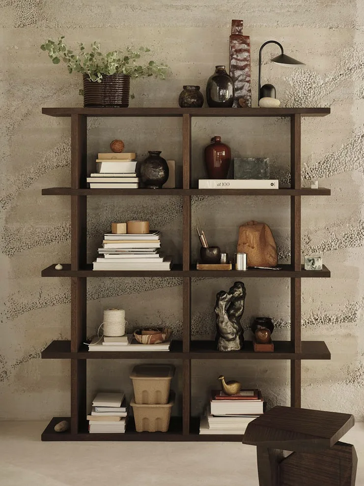 Dark wooden shelving unit filled with books, plants, and decorative objects against a textured wall.