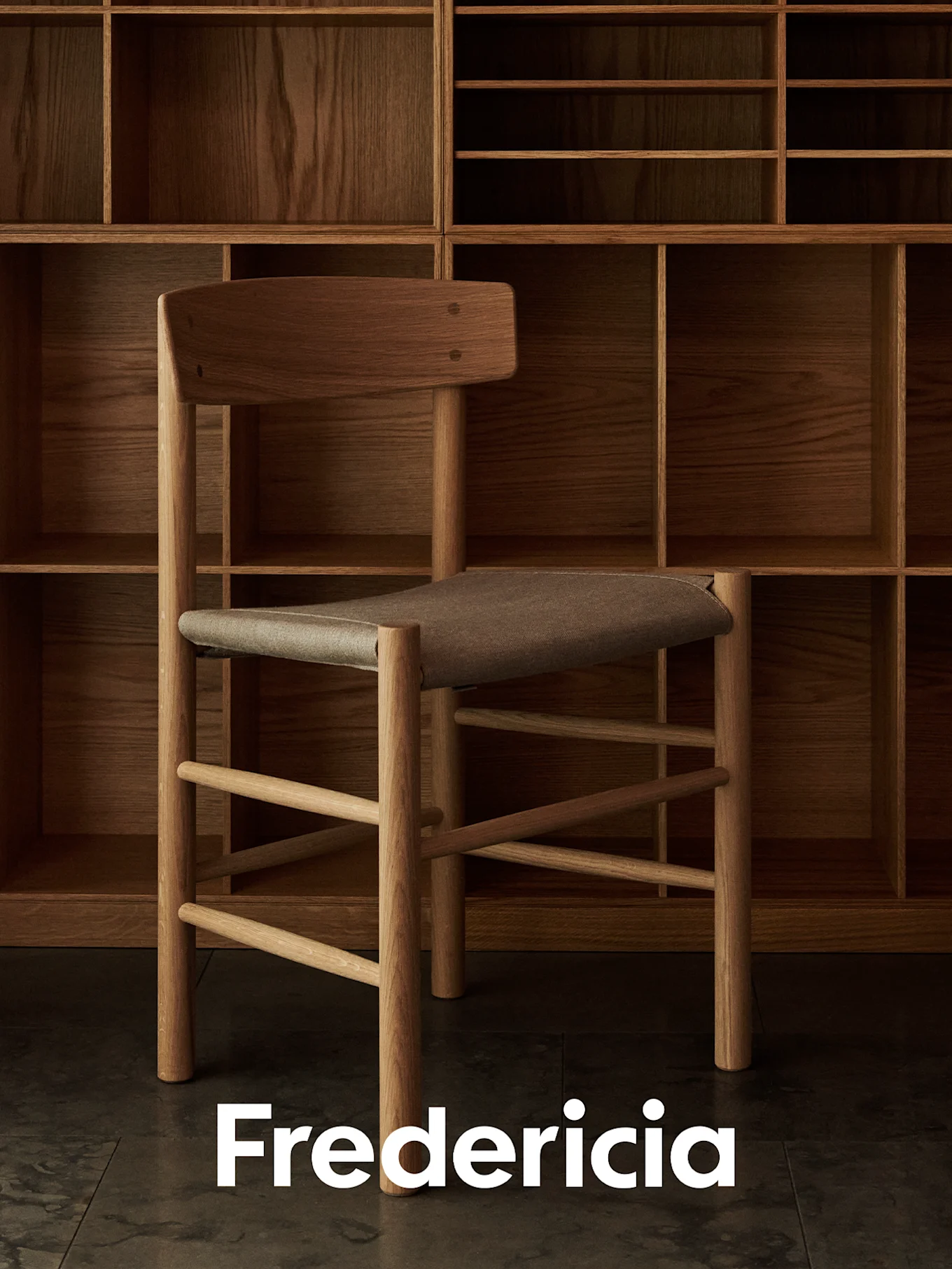 Light wooden chair with brown fabric seat in front of a dark wood shelving unit. Fredericia logo at bottom.